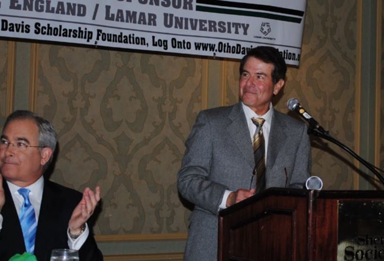 A man stands at a podium in front of a sign that says lamar university