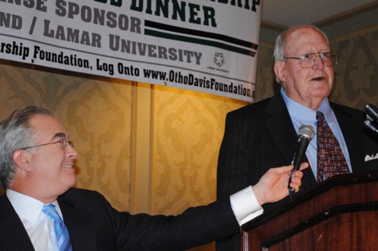 A man giving a speech in front of a sign that says dinner
