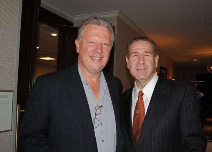 Two men in suits and ties pose for a picture