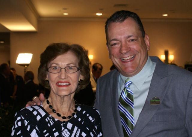 A man in a suit and tie poses with an older woman