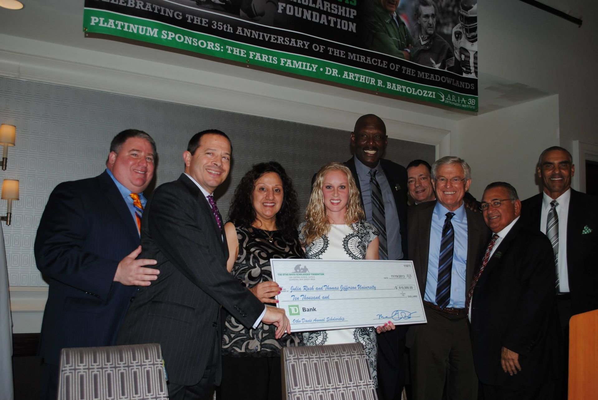 A group of people standing around a woman holding a large check