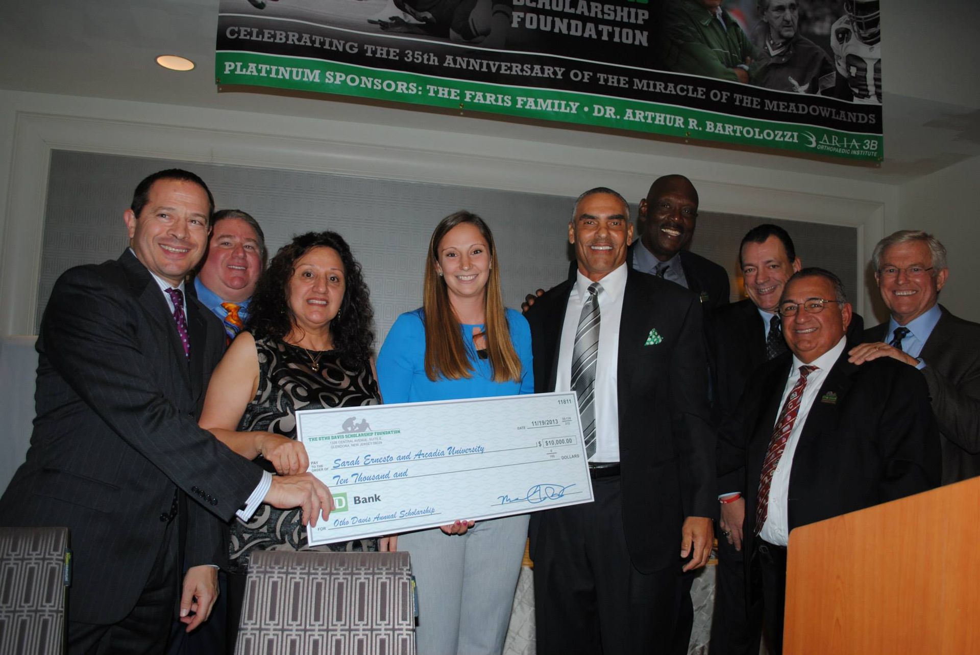 A group of people standing around a woman holding a large check