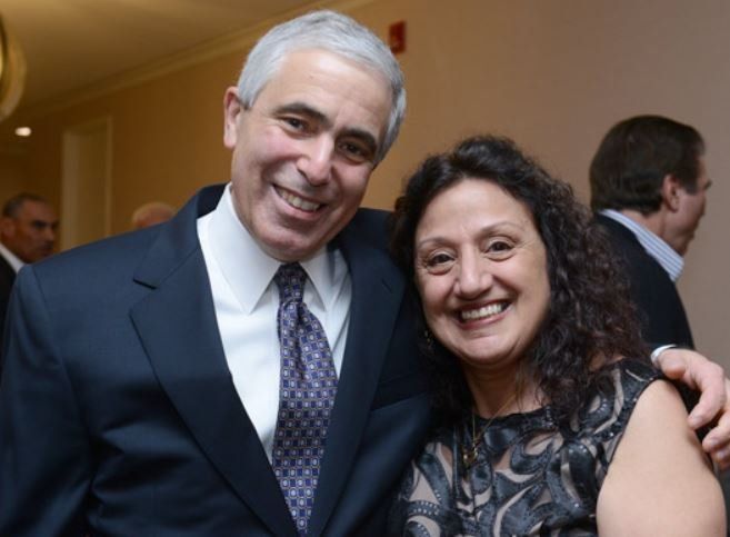A man in a suit and tie poses with a woman in a black dress