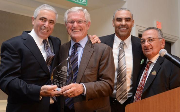 Four men in suits and ties are posing for a picture