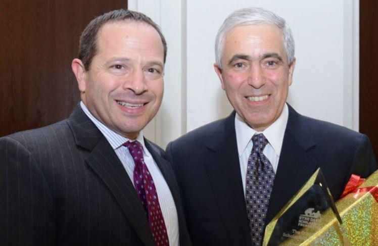 Two men in suits and ties are posing for a picture