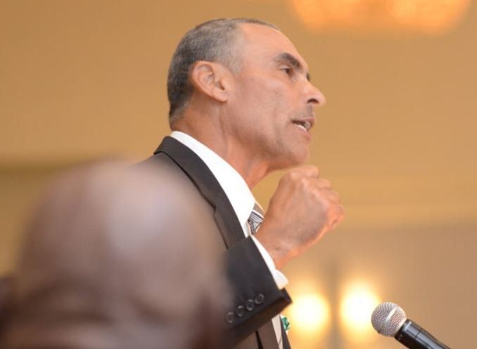 A man in a suit and tie is speaking into a microphone