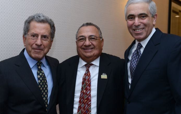 Three men in suits and ties pose for a picture