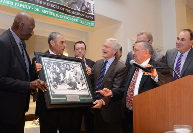 A group of men standing around a podium holding a framed picture