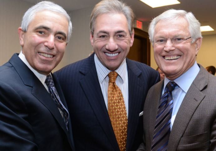 Three men in suits and ties are posing for a picture