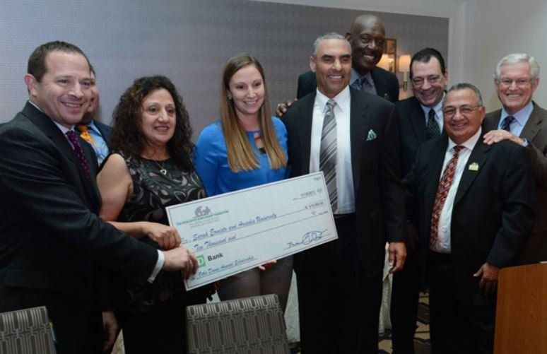 A group of people are posing for a picture while holding a large check.