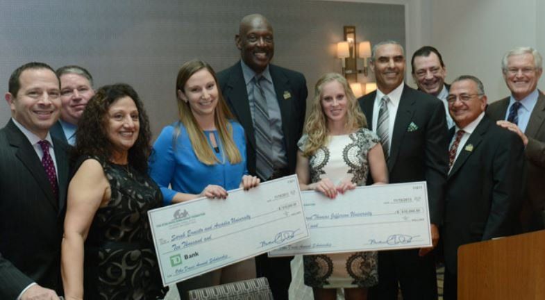 A group of people standing next to each other holding checks.