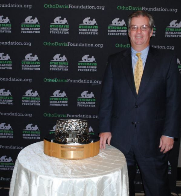 A man in a suit and tie stands in front of a wall that says ohiodavisfoundation.org
