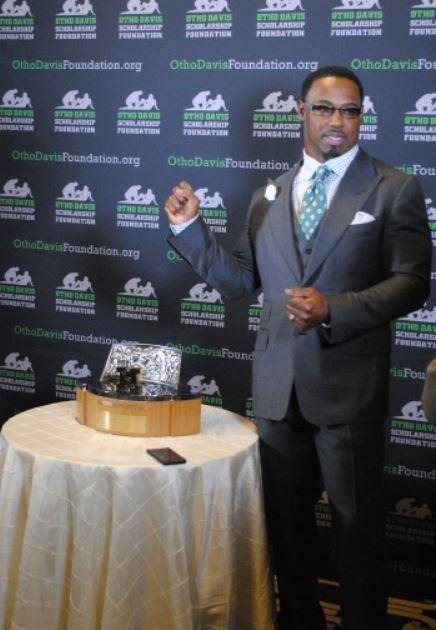 A man in a suit and tie stands next to a table