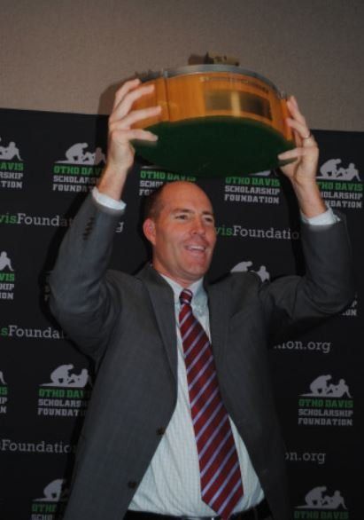 A man in a suit and tie is holding a trophy in his hands
