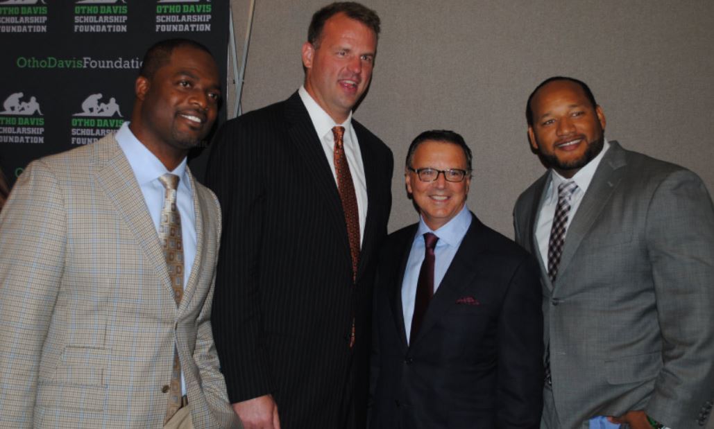 Four men in suits and ties pose for a picture