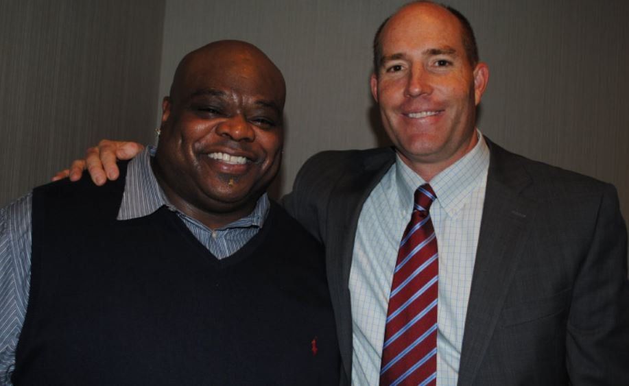 Two men in suits and ties are posing for a picture.