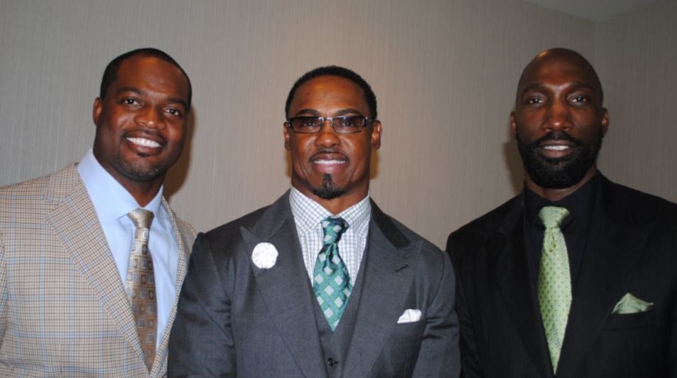 Three men in suits and ties are posing for a picture