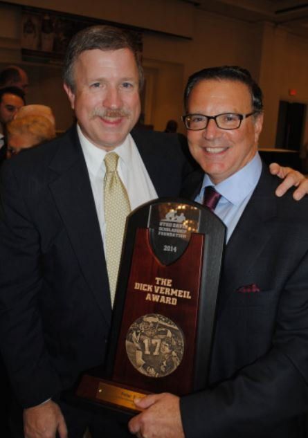 Two men are holding a trophy that says the rick vermeil award