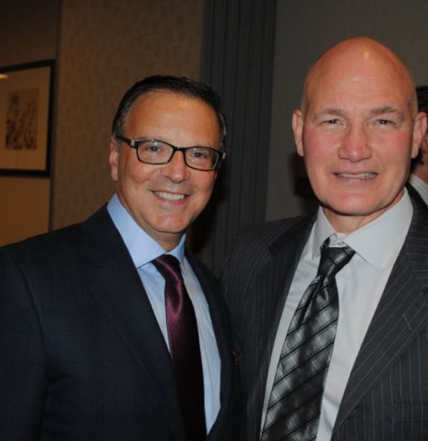 Two men in suits and ties pose for a picture