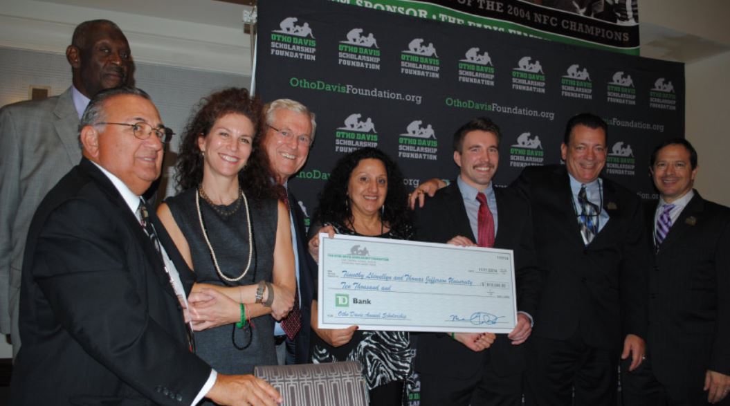 A group of people are holding a large check