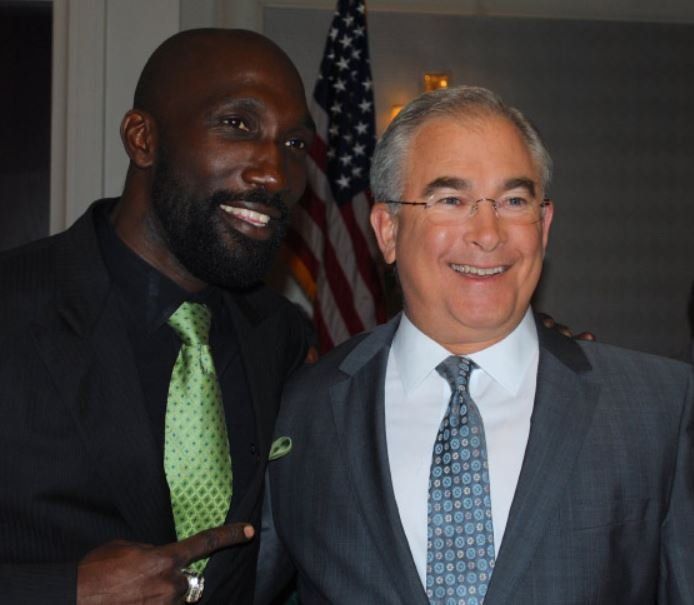 Two men are posing for a picture in front of an american flag