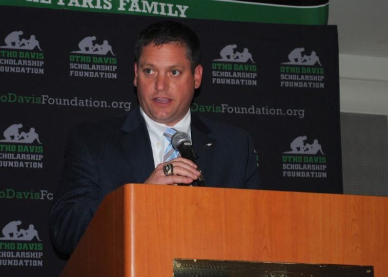A man in a suit and tie is standing at a podium holding a microphone