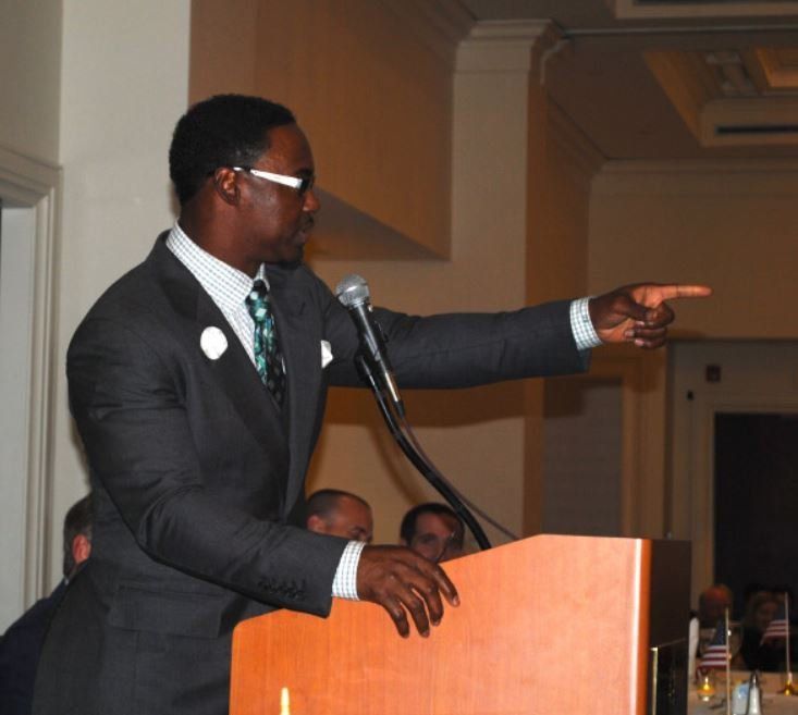 A man in a suit and tie is giving a speech at a podium