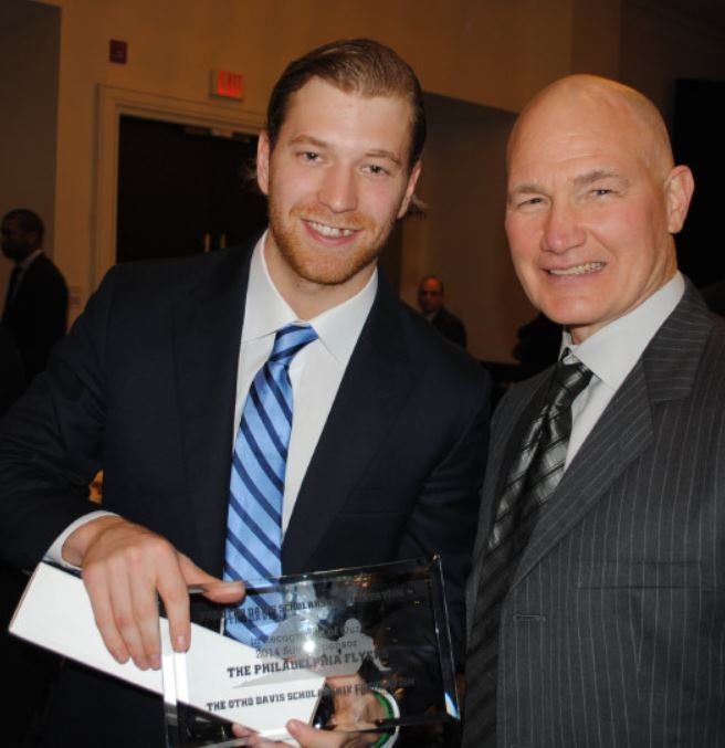 A man in a suit and tie is holding a trophy that says the philanthropist