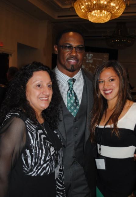 A man in a suit and tie poses with two women