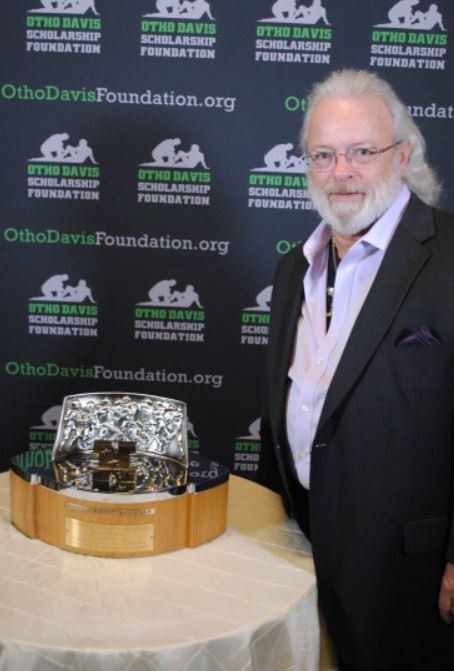 A man in a suit stands in front of a wall that says ortho davis foundation