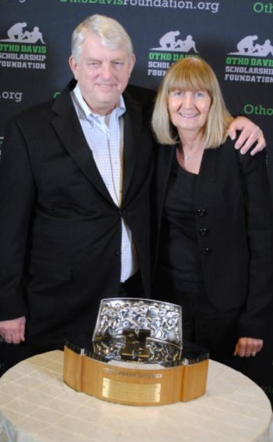 A man and a woman standing next to a trophy