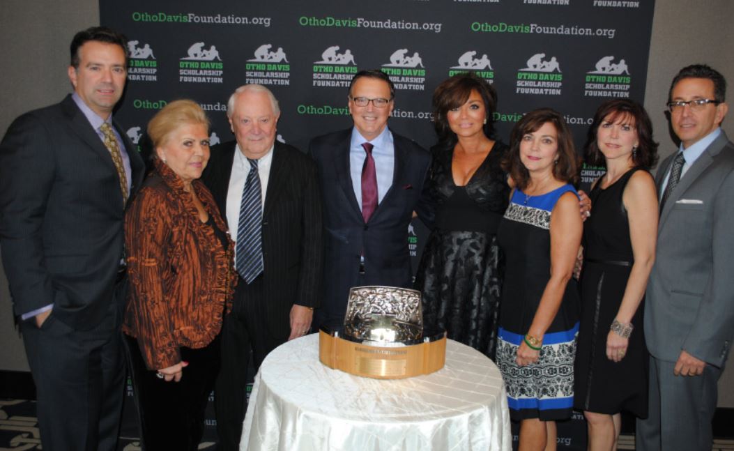 A group of people standing around a table with a trophy on it