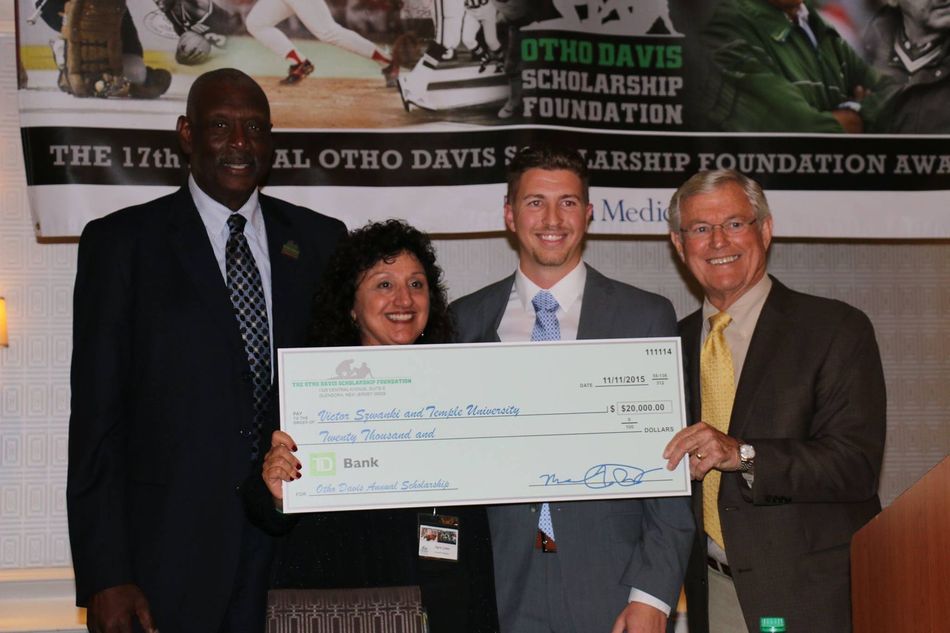 A man in a suit and tie is holding a large check