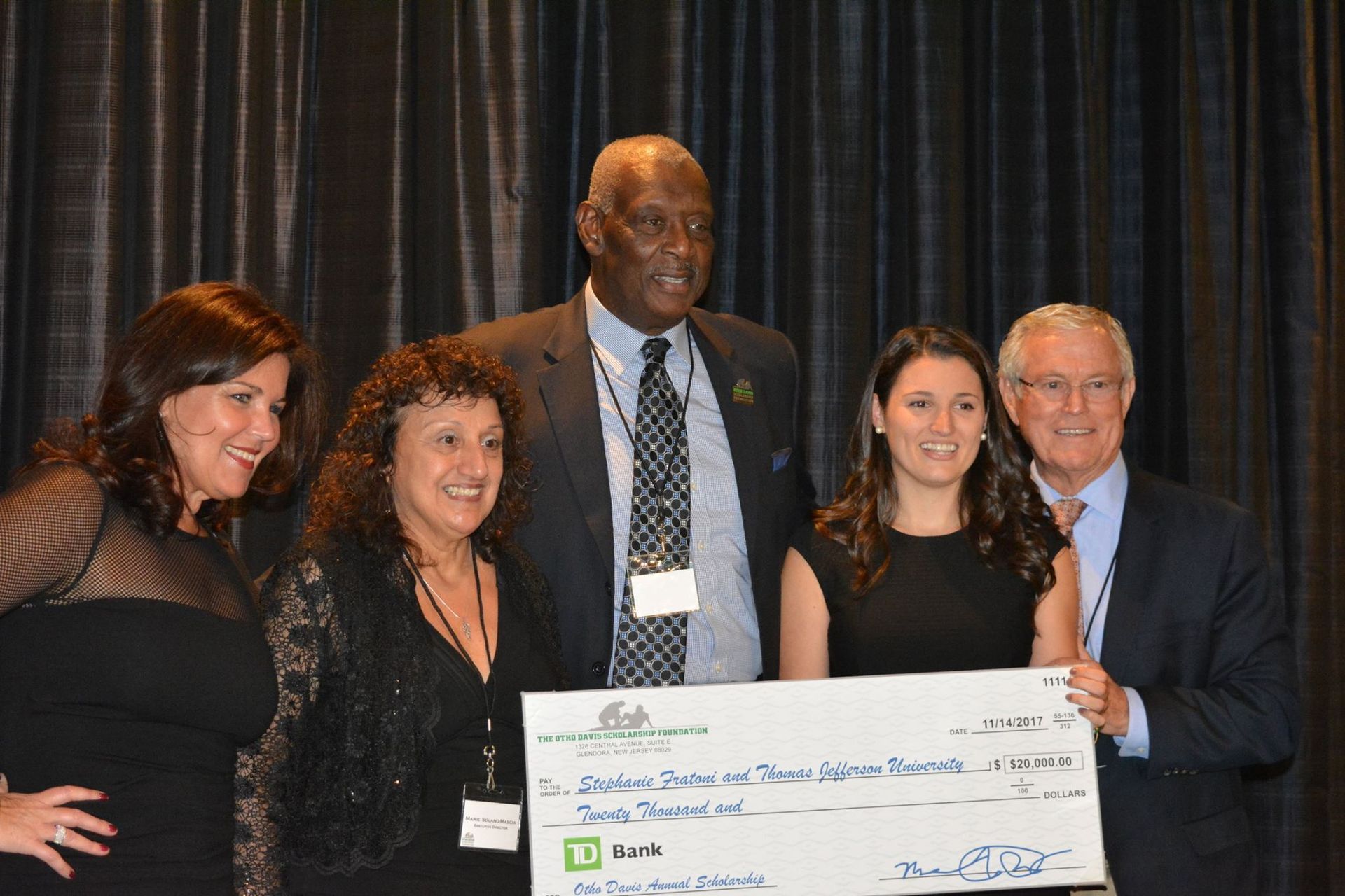 A group of people standing next to each other holding a large check.
