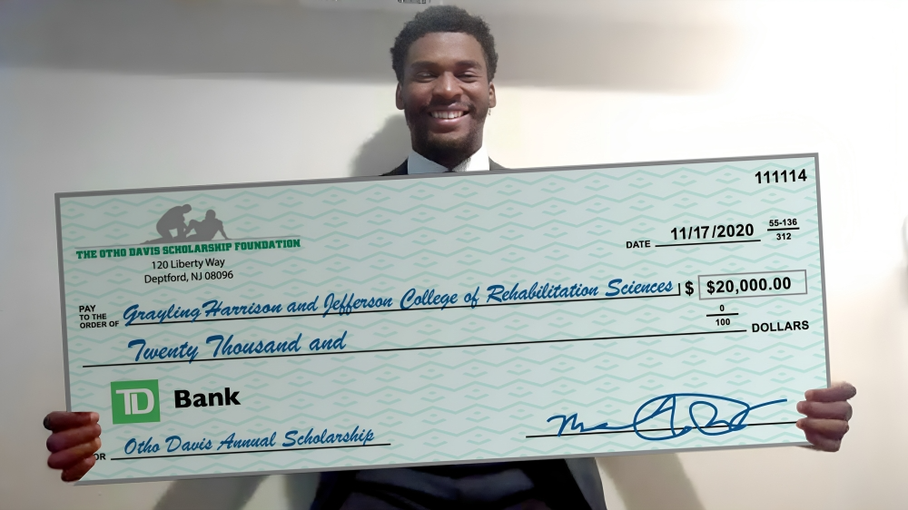 A man is holding a large check from d bank