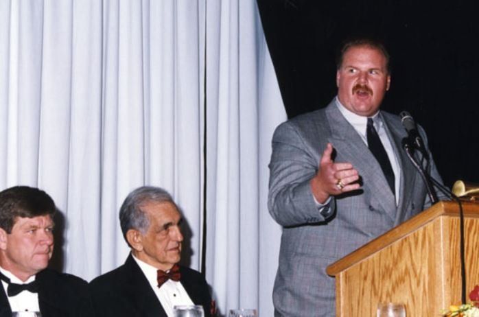 A man in a suit and tie is giving a speech at a podium