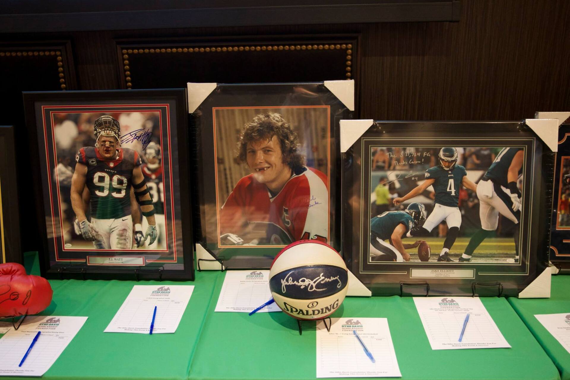 A basketball is sitting on a table surrounded by framed pictures of football players.