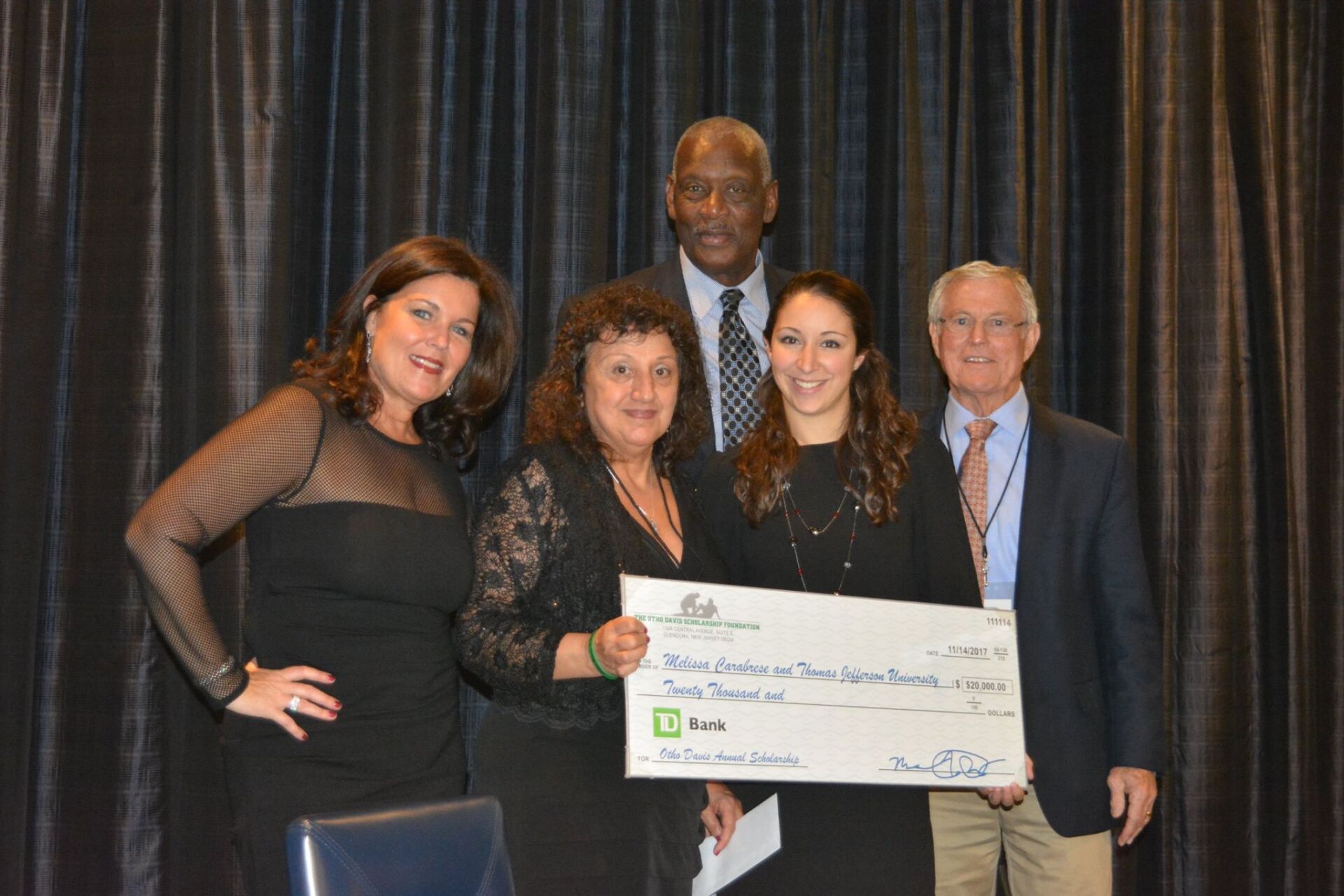 A group of people standing next to each other holding a large check.