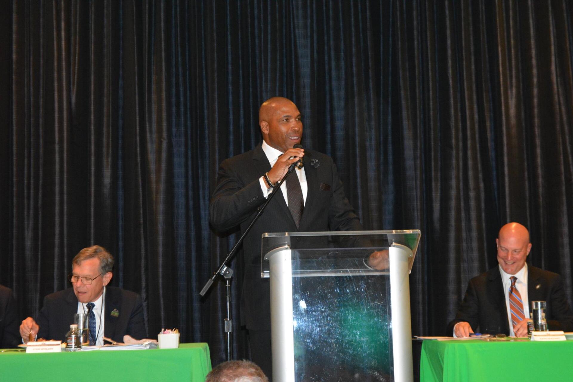 A man in a suit and tie is standing at a podium giving a speech.