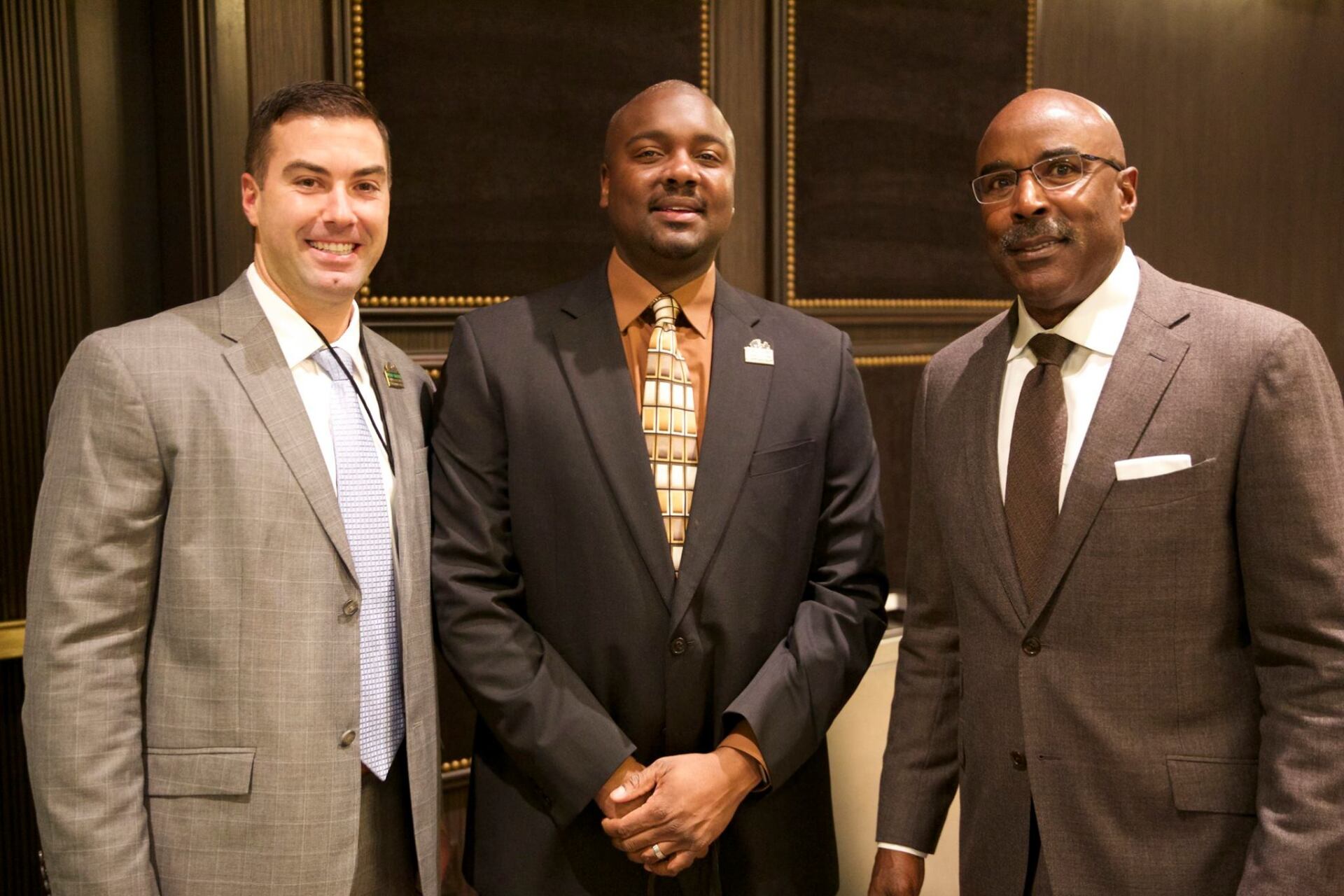 Three men in suits and ties are posing for a picture
