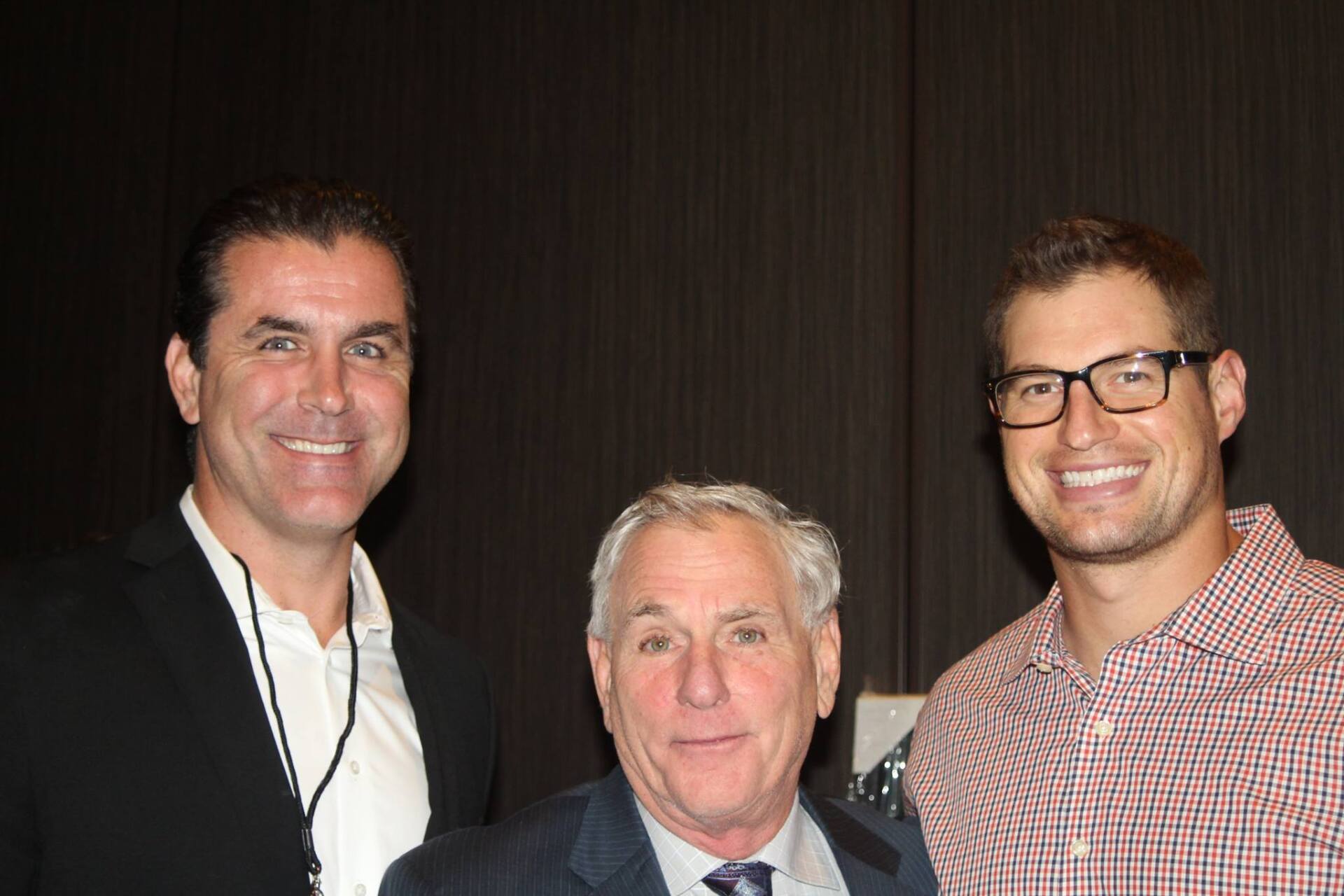 Three men are posing for a picture together and smiling for the camera.