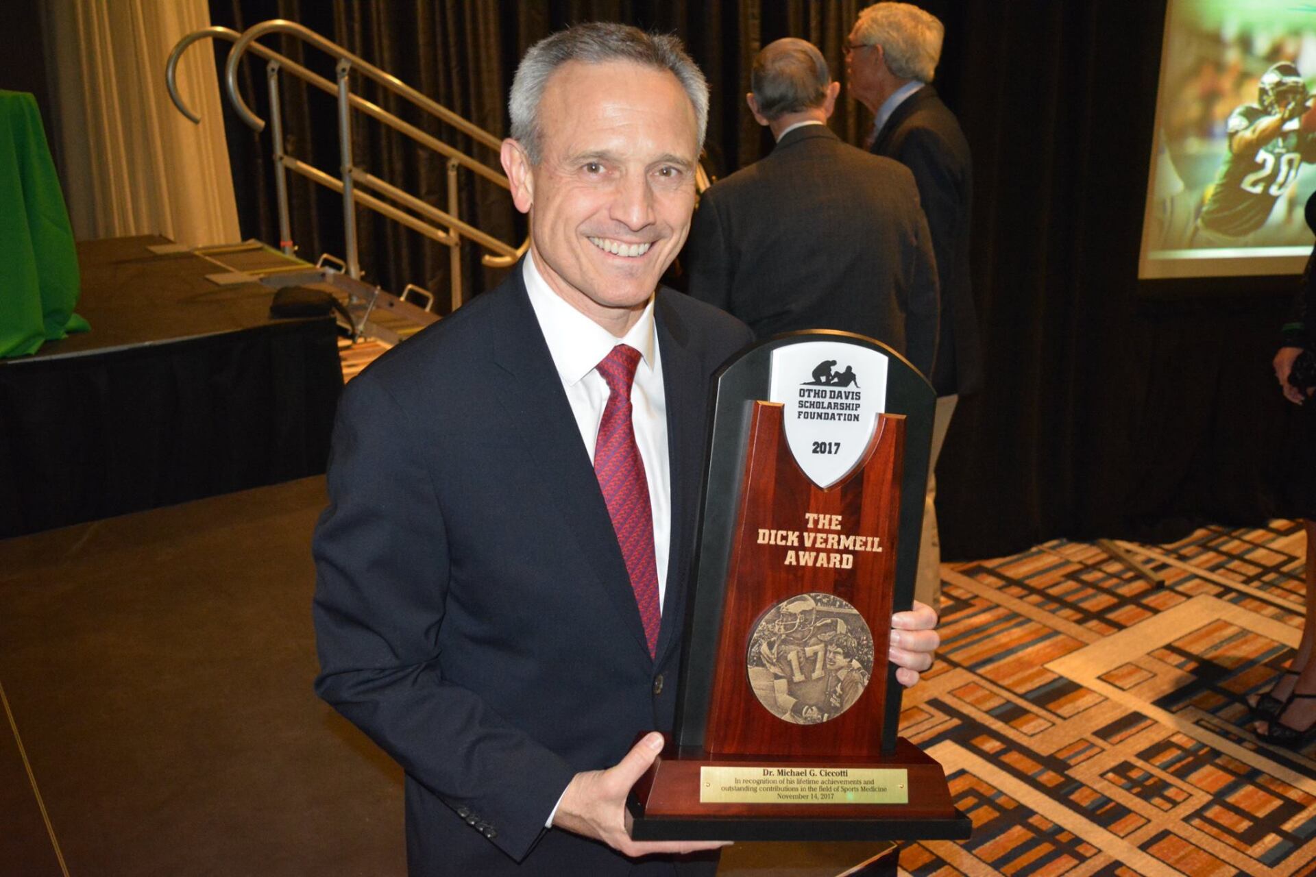 A man in a suit and tie is holding a trophy.