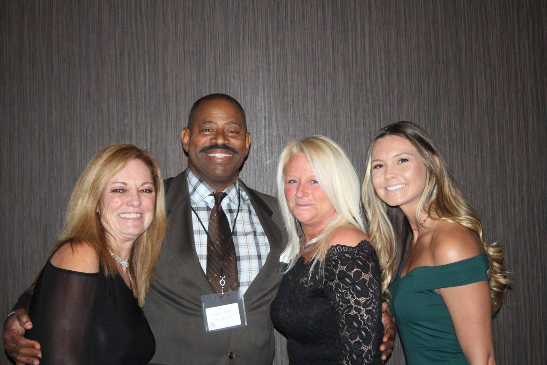 A man in a suit and tie is posing for a picture with three women.