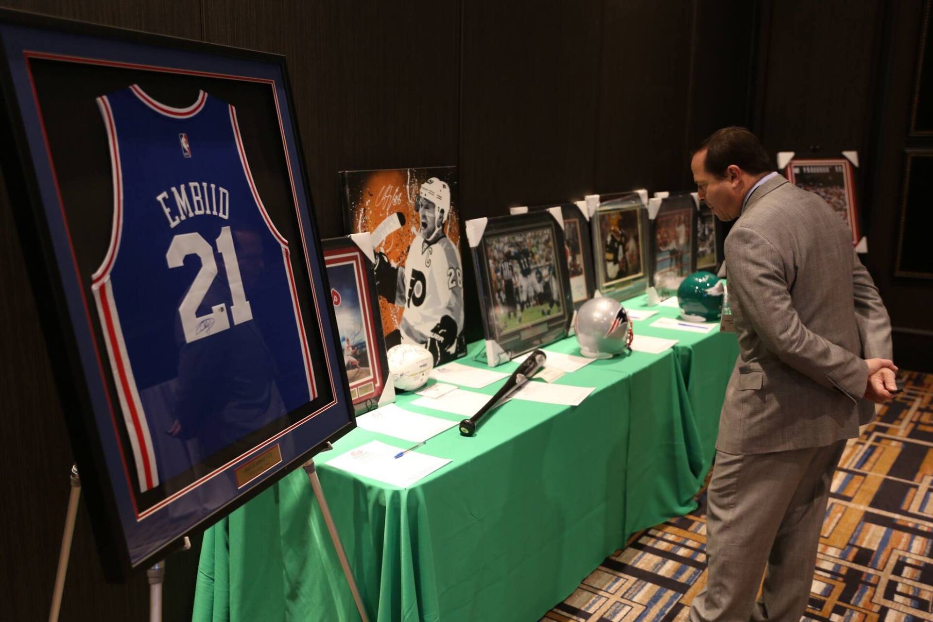 A man in a suit is looking at a basketball jersey with the number 21 on it