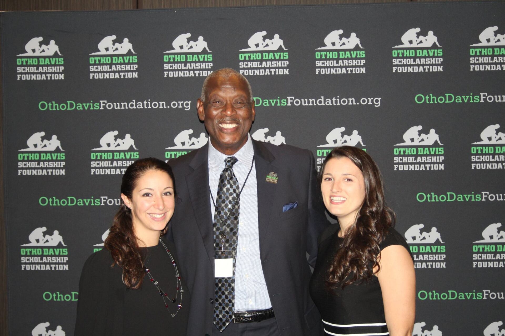 A man and two women are posing for a picture in front of a banner that says othdavisfoundation.org