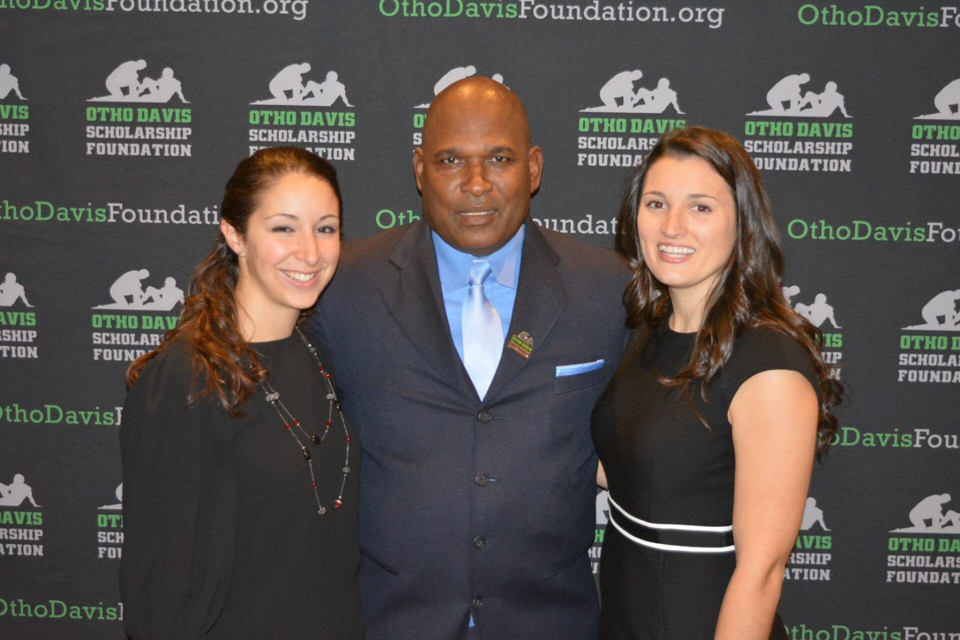 A man in a suit and tie poses with two women
