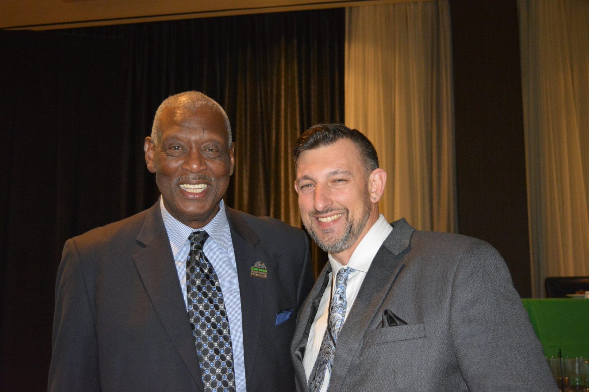 Two men in suits and ties are posing for a picture.