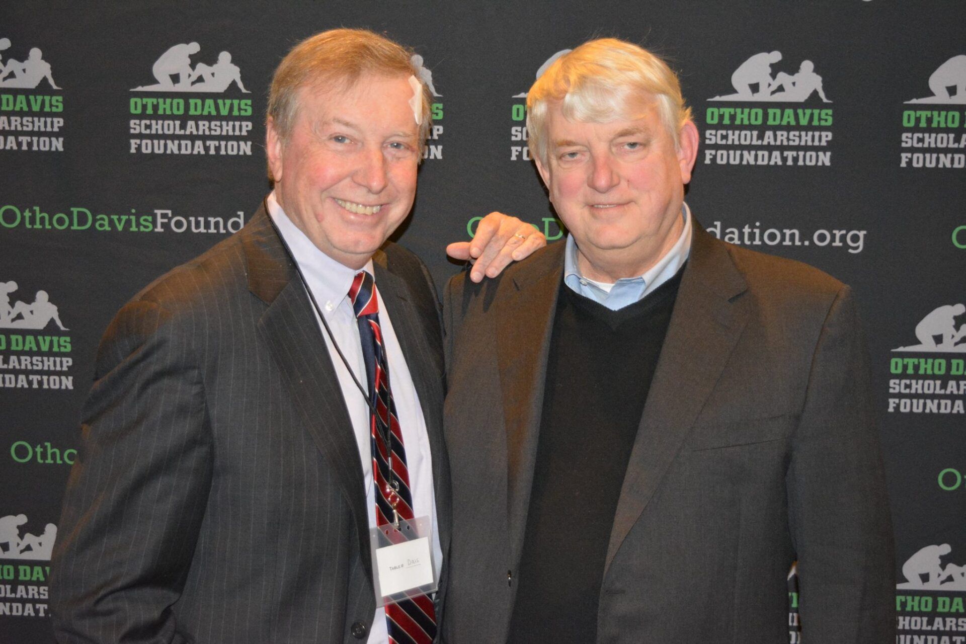 Two men are posing for a picture in front of a backdrop that says ortho davis scholarship foundation