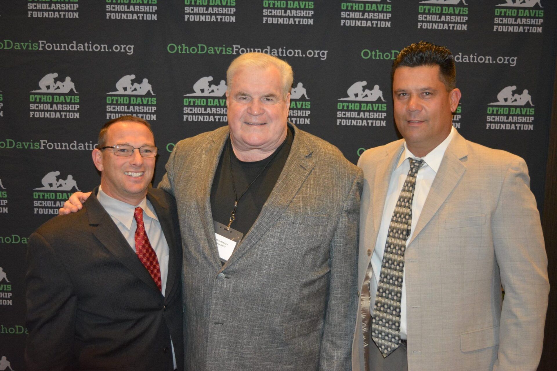 Three men in suits and ties pose for a picture