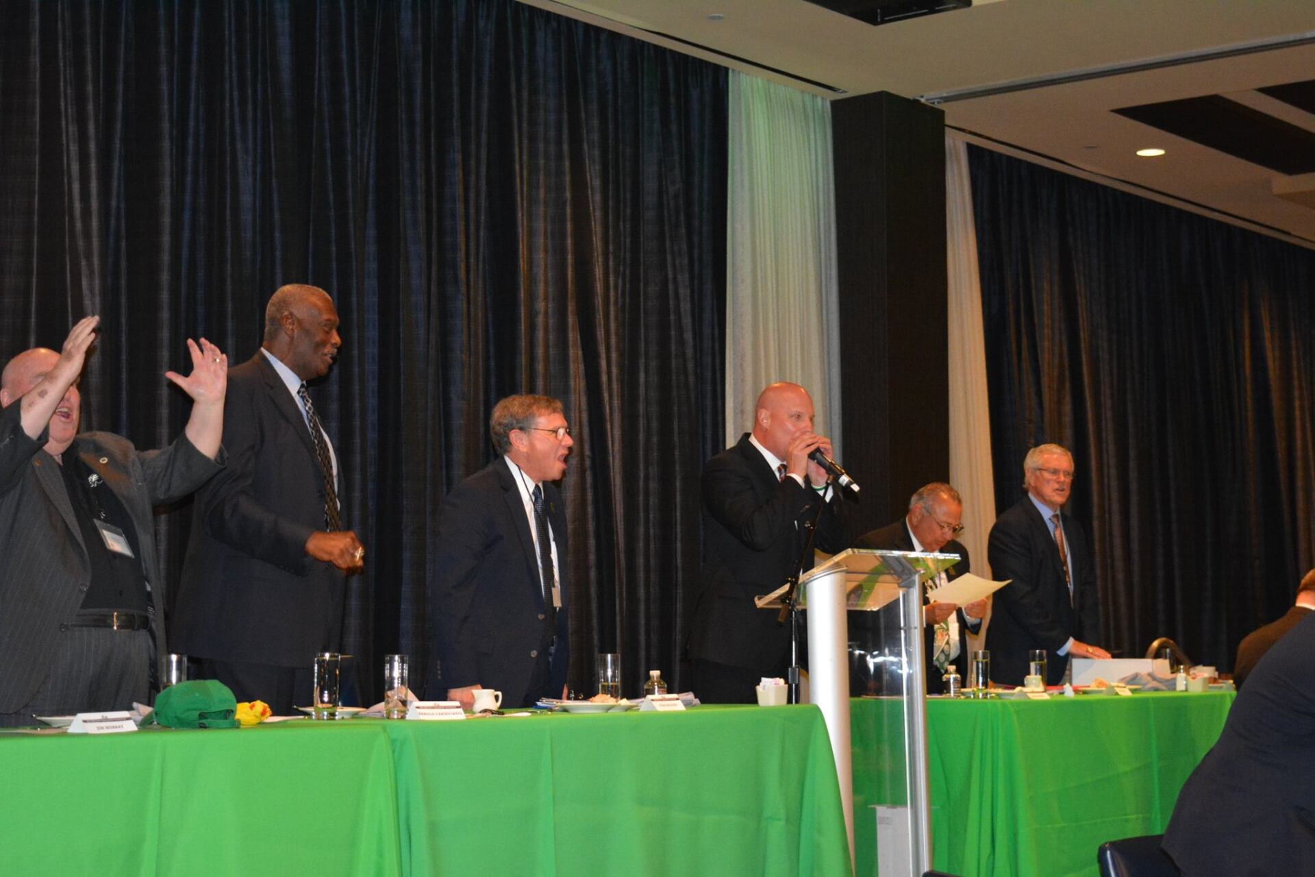 A group of men are sitting at a table with microphones in front of them